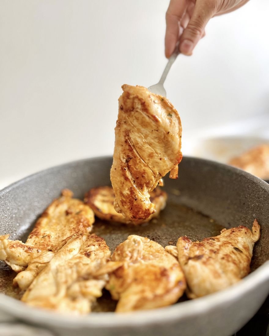 Filés de frango dourando na frigideira
