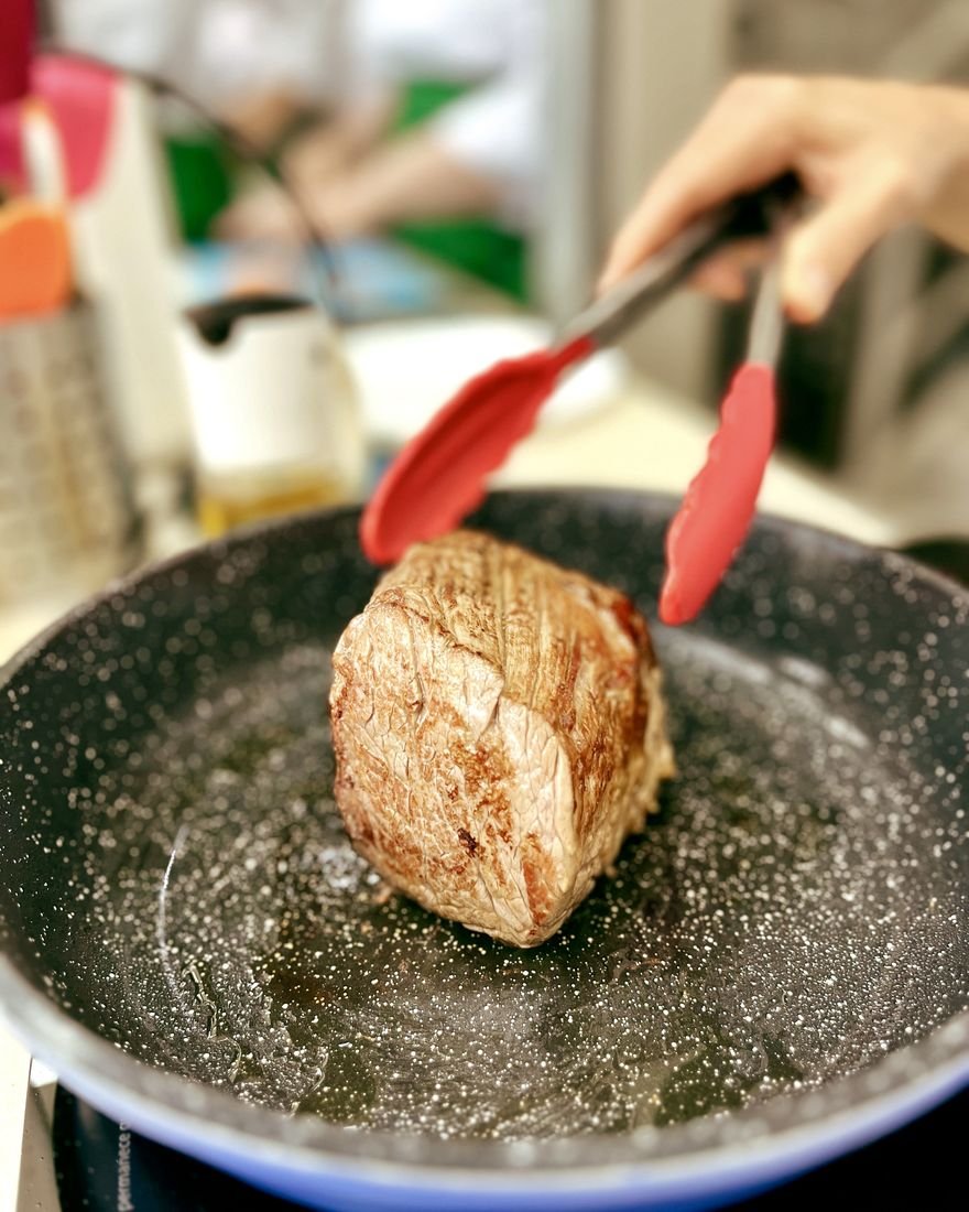 Selagem de peça de carne na frigideira durante aula prática